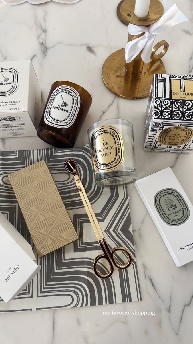 A curated selection of luxury housewarming gifts including designer candles, fine tableware and elegant home accessories styled on a marble surface