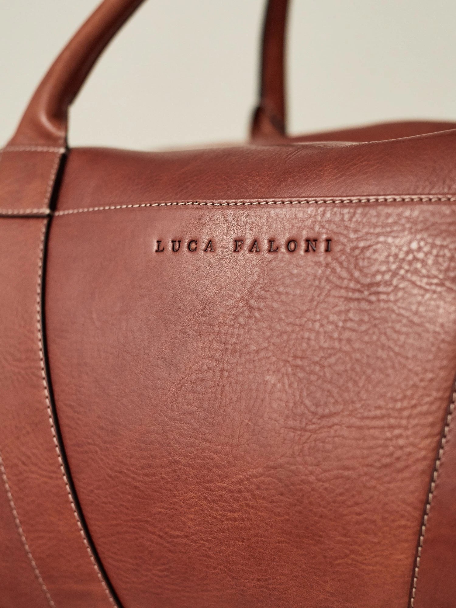 Man carrying Luca Faloni full grain leather weekender bag in cognac brown