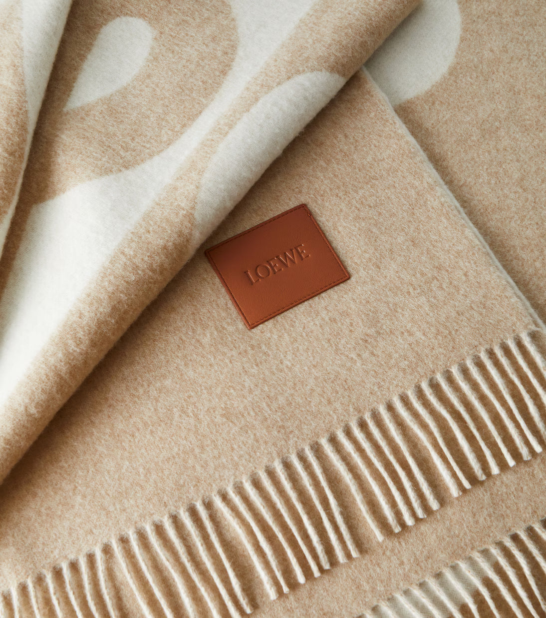 Beige blanket with white heart patterns and a Loewe label.
