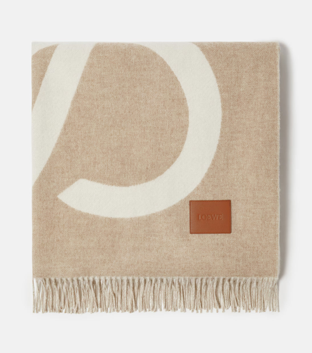 Beige blanket with a large white letter 'P' and a brown label on a light gray background